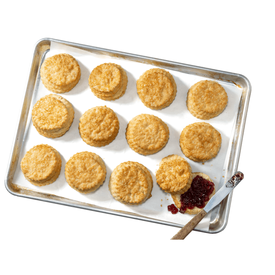 A flaky buttermilk biscuit beside a dish of berry jam